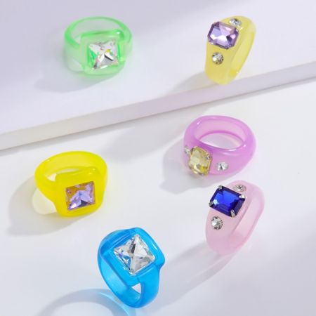 Acrylringen met rhinestones - Een collectie van zes levendige acrylringen met verschillende kleurrijke rhinestones, die de variëteit tonen die beschikbaar is van JR Fashion Accessories.