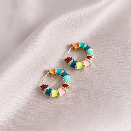 Detailed shot of the colorful hoop earrings, showcasing the gold base and intricate multi-color enamel details.