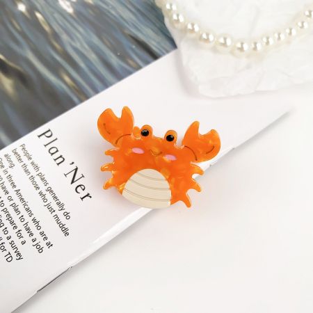 遊び心のあるアクセサリーのためのかわいいオレンジのカニ型ヘアクリップ。