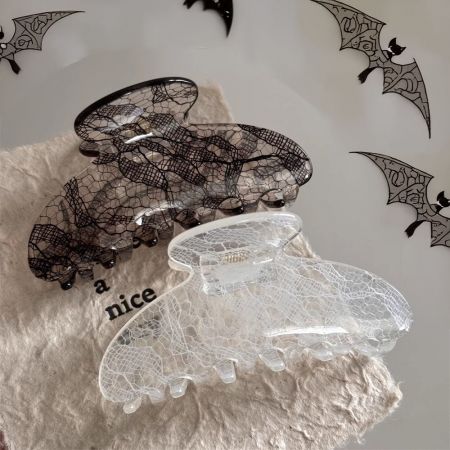Clipes de cabelo pretos e transparentes com padrão jacquard exibidos em um fundo neutro.