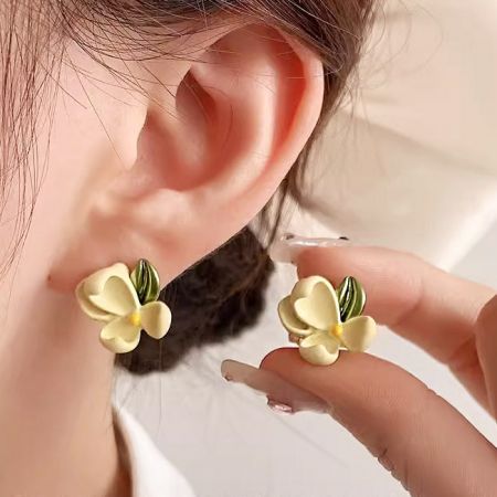 Modèle portant des boucles d'oreilles en fleur de gardénia jaune, montrant leur taille et leur apparence.