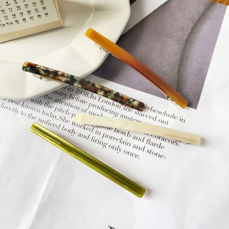 Three acetate hair clips in different colors and patterns, showcasing the product variety.