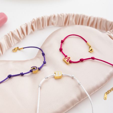 A、B、Cのイニシャルが表示されたホールセールエナメルレターフレンドシップブレスレットは、柔らかいサテンポーチに入っており、パーソナライズされたギフトに最適です。