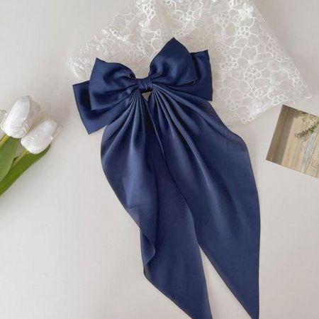 Um sofisticado prendedor de cabelo em forma de laço de cauda longa de cetim azul escuro.