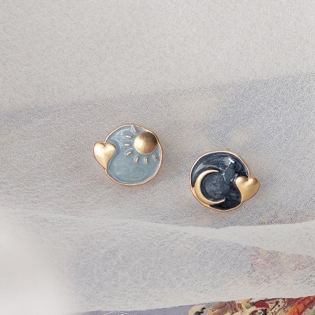 A pair of day and night themed earrings, showcasing the sun and moon designs.