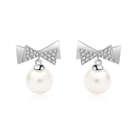 Boucles d'oreilles en perles Bow de 7 mm. - Gros plan des boucles d'oreilles en perles Bow de 7 mm, présentant le design complexe en forme de bow incrusté de diamants et la perle d'eau douce blanche lustrée.
