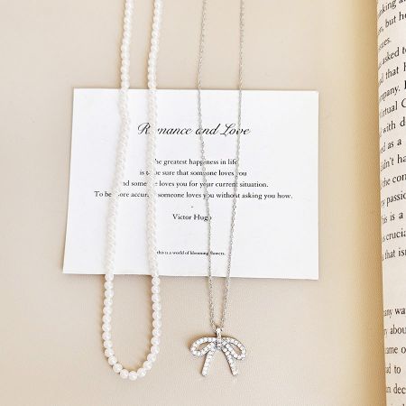 Le collier en zircon avec nœud en argent sterling est affiché élégamment sur un fond de citation romantique.