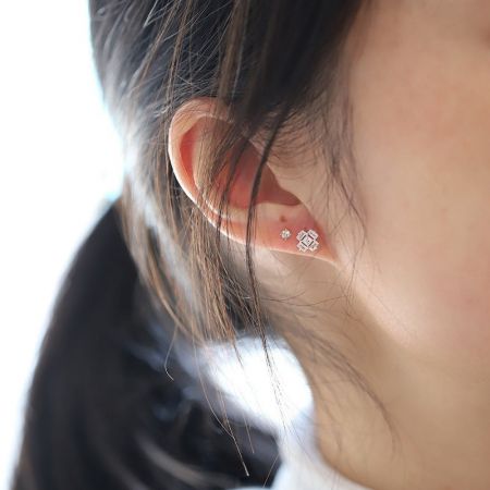 Primo piano di un modello che indossa gli orecchini a forma di cubo di ghiaccio con zirconia cubica.
