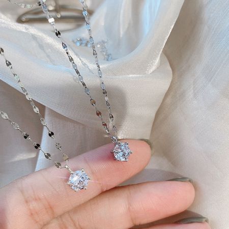2つのスターリングシルバーの6爪ジルコンネックレスを持つ手が、その輝きとデザインを披露しています。