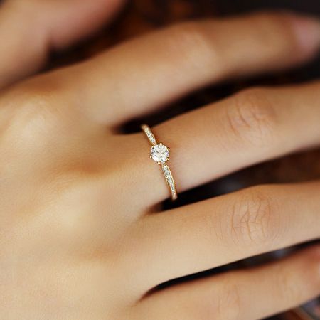 Bagues solitaires classiques en argent sterling 925 plaquées or à six griffes en gros - Une bague solitaire en zircon cubique plaquée or à six griffes en argent sterling 925 du lot de gros, portée au doigt d'une femme pour montrer l'échelle et l'éclat.