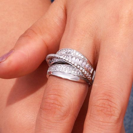 Detailed product shot of the multi-layered cubic zirconia brass ring set on a soft pink background.