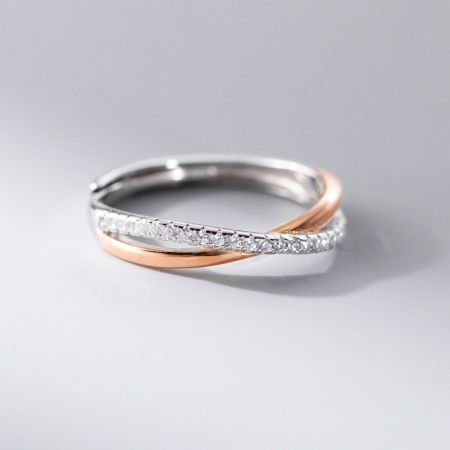 Nahaufnahme eines luxuriösen Möbius-Rings mit verflochtenen Silber- und Roségoldbändern, verziert mit funkelndem Zirkonia.
