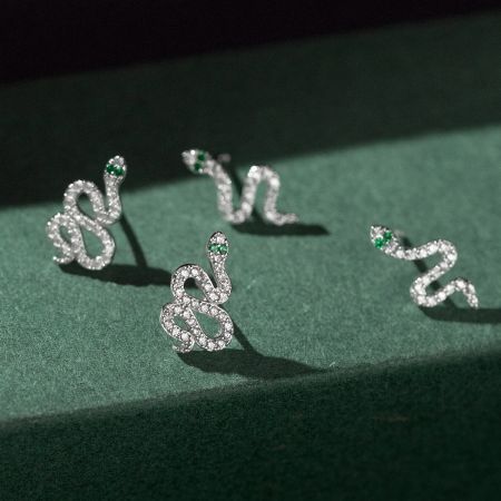 Vista dettagliata degli orecchini a forma di serpente incastonati con diamanti che evidenziano gli occhi in pietra verde.