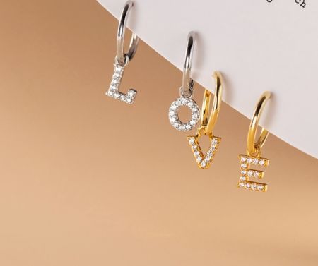 Orecchini a Cerchio Iniziali in Argento Sterling 925 - Una collezione di orecchini a cerchio iniziali in argento sterling 925 con vari charm a forma di lettere e simboli incastonati con zirconia cubica scintillante.