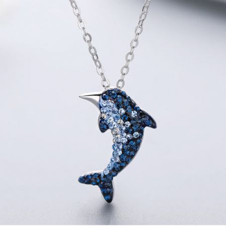 Un collar de colgante de delfín bellamente elaborado, adornado con vibrantes piedras preciosas azules.