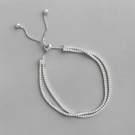 Nahaufnahme des doppelt-strängigen silbernen Tennisarmbands, das die quadratisch geschliffenen Zirkonia-Steine detailliert.