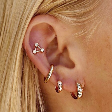 Orecchini Huggie a Cerchio in Argento Sterling 925 con CZ a Forma di Stella (Set di 5 Paia) - Una modella che mostra più orecchini huggie a cerchio in argento sterling 925 con CZ a forma di stella in oro, evidenziando la loro vestibilità elegante.