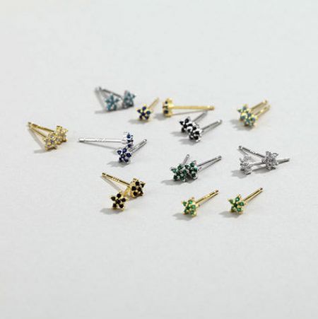 Un assortimento di piccoli orecchini a perno a forma di fiore in finiture argento e oro.