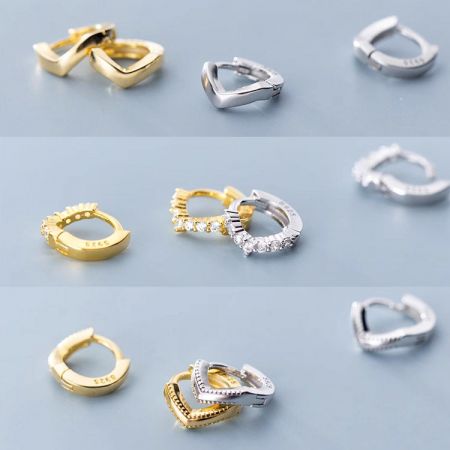 Uma variedade de brincos huggie hoop em forma de onda, tanto em ouro quanto em prata.
