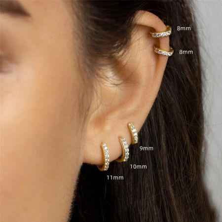 Un modello di orecchio che mostra come appaiono indossati i diversi formati degli orecchini a cerchio huggie in zirconia.