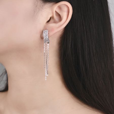 Modello che indossa orecchini a frangia d'argento eleganti, mostrando la loro lunghezza e movimento.