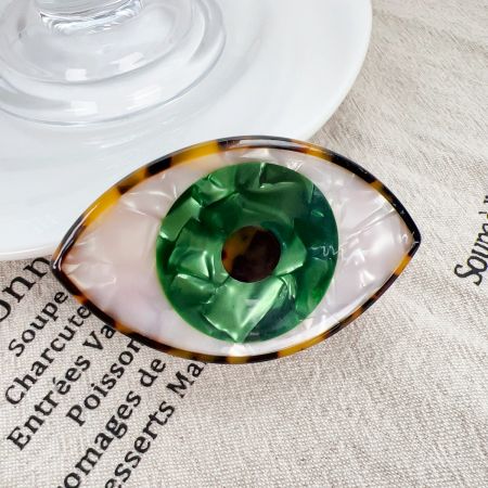 Clipe de cabelo verde vibrante com Olho Turco mostrado de perto, exibindo sua cor única e padrão de tartaruga.