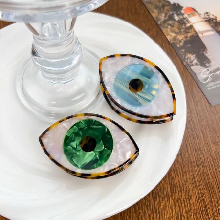 Uma disposição estilosa dos clipes de cabelo azul e verde com Olho Turco, apresentados como acessórios da moda.
