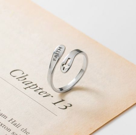 Bague en croix de foi en argent sterling 925 - Une bague en argent sterling 925 gravée du mot 'FOI' et d'un symbole de croix, reposant sur un livre ouvert pour mettre en valeur son design inspirant.