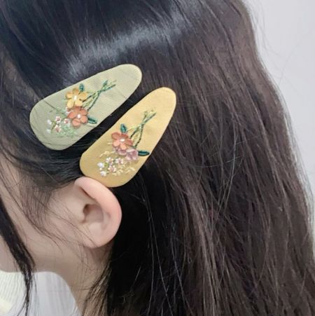 ダークブラウンの髪に付けた2つの花柄ヘアクリップのクローズアップ。