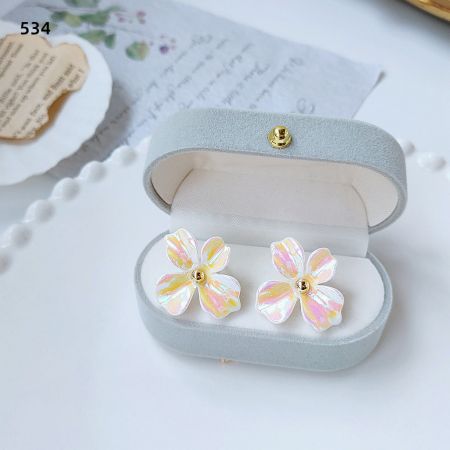 青いジュエリーボックスに入った虹色効果のフラワーイヤリング5ペアのセット。