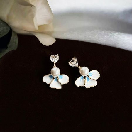 真珠とクリスタルのディテールを強調した花型のぶら下がりイヤリングの詳細ショット。
