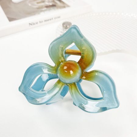 Een meerkleurige plumeria haarclip met tinten blauw, groen en geel.