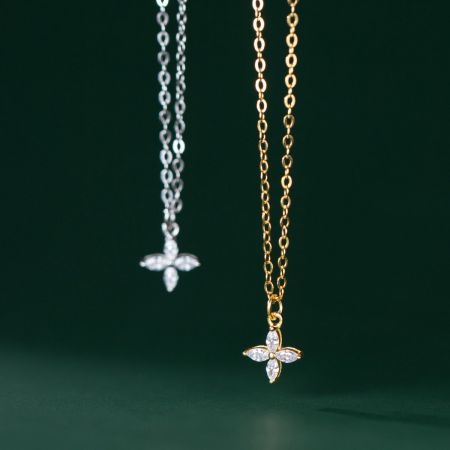 Conjunto de collar de flor de trébol de cuatro hojas pequeño de plata esterlina 925. - Un par de collares de flores de trébol de cuatro hojas de plata esterlina 925, uno con un acabado de plata pulida y el otro con un acabado dorado radiante, ambos con delicados detalles de piedras preciosas.