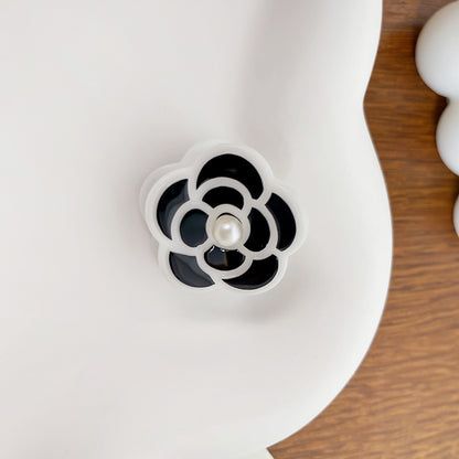 Gedetailleerd uitzicht op een witte mini camelia bloem haarclip met een centrale parelaccent.