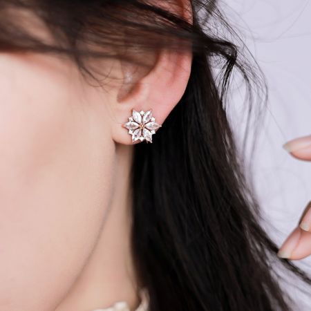 Close-up of a rose gold flower-shaped earring with sparkling cubic zirconia.