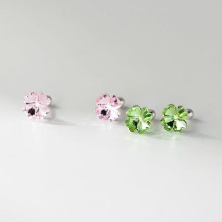 Close-up dos brincos de trevo de quatro folhas de cristal rosa e verde em prata esterlina.