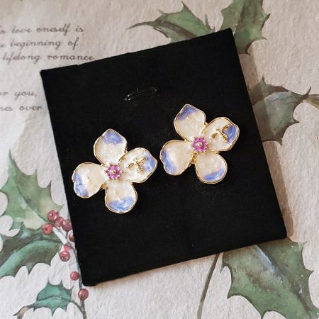 Detailed view of the flower earrings showing the gold bee accent and pink gemstone.