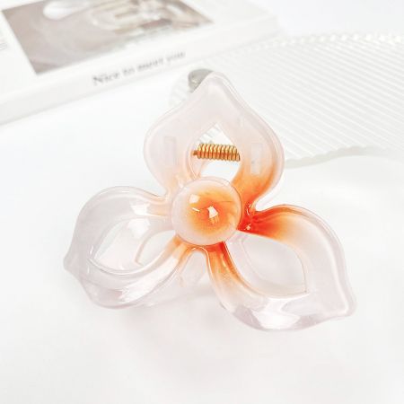 Close-up van een frangipani bloemen haarclip met een prachtig wit en oranje gradient ontwerp.