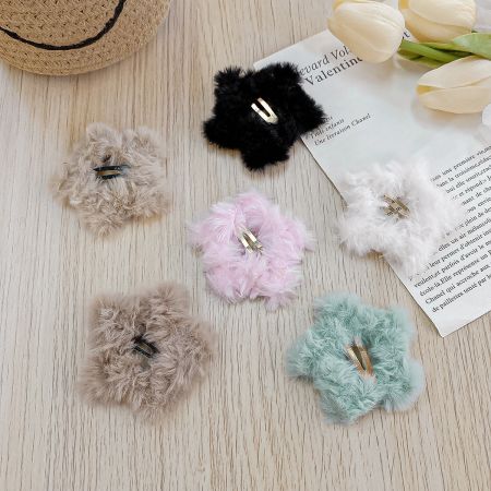 Une collection de pinces à cheveux en forme d'étoile en peluche douce dans diverses couleurs, y compris rose, bleu, beige, blanc et noir.