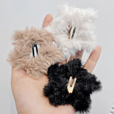 Un ensemble de trois pinces à cheveux en peluche étoile dans des tons neutres : beige, blanc et noir.