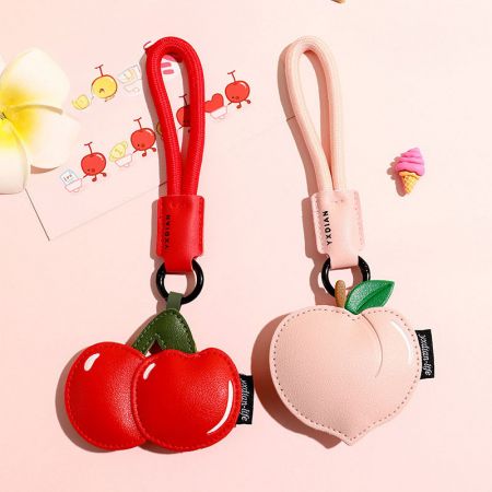 Una colección de llaveros de frutas que incluye un diseño de cereza roja y un durazno rosa.