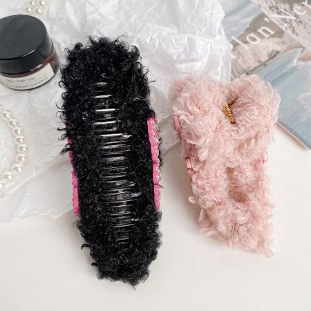 Dois clipes de cabelo de pelúcia, um rosa e um preto, exibidos com produtos de beleza.
