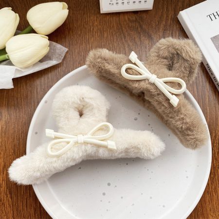 白と茶色のふわふわのヘアクリップを並べて見た様子で、どちらも繊細な白いリボンで飾られています。