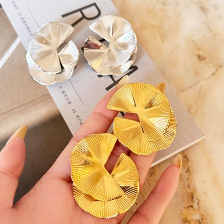 Een paar gouden en een paar zilveren ginkgo blad oorbellen.
