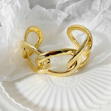 A gold cuff bracelet with a modern, abstract design.