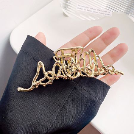 Detailed shot of the abstract gold hair clip, highlighting its unique shape.