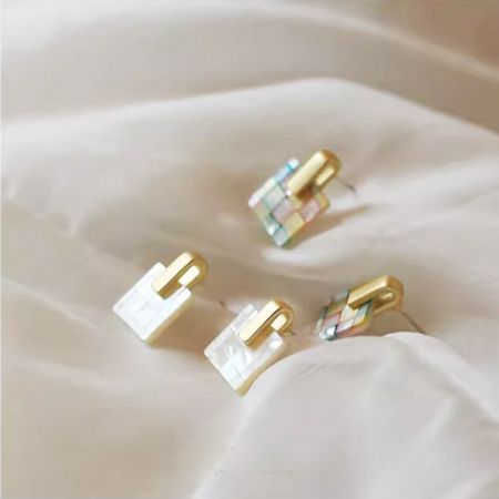 金と白を含む異なる色のパターンを展示するモザイクスタッドイヤリングの3ペア。