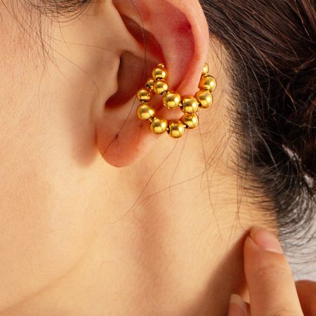 Arete de perlas con diseño de bola dorada en acero inoxidable (5 pares) - Una mujer usando el arete de perlas con diseño de bola dorada en acero inoxidable, mostrando su ajuste y estilo elegantes.
