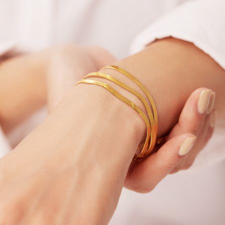 Muñeca del modelo adornada con el elegante conjunto de 5 pulseras de cadena de serpiente de oro.