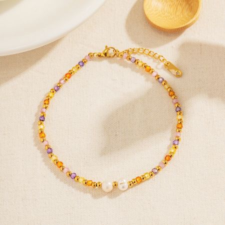 Detailed view of a gold anklet with multicolored beads and pearls from the set.